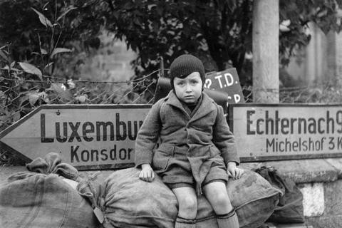 Ein siebenjähriger Junge wartet an einer Kreuzung auf seinen Weitertransport: Dieses Bild entstand 1945 beim Vormarsch der US-Truppen in Luxemburg.  Foto: Lee Miller Archives, England 2013 