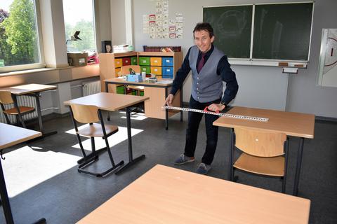 IGS-Schulleiter Dieter Koch-Schumacher demonstriert die neuen Abstandsregeln im Klassenzimmer mit dem Zollstock. Foto: Nathalie Doleschel