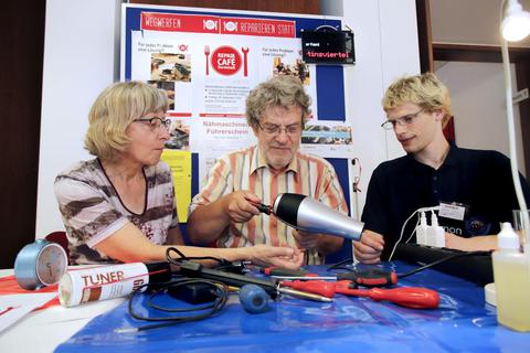 Am Informationsstand des Repair-Cafés im Martinsviertel repariert Matthias Rewald (Mitte) einen abgegebenen Haartrockner. Karin Rewald (links) und Simon Junga (rechts) schauen ihm dabei zu. Foto: Andreas Kelm  Foto: Andreas Kelm