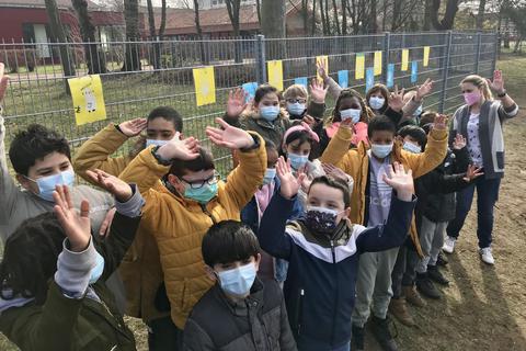 Kinder der Ernst-Elias-Niebergall-Schule jubeln über ihre Ukraine-Aktion: Sie haben blau-gelbe Bilder mit Friedensmotiven an ihren Zaun gehängt. Foto: Thomas Wolff