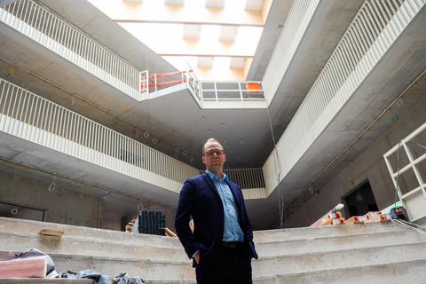 Darmstadts Bildungsdezernent Holger Klötzner (Volt) posiert auf der Baustelle der Heinrich-Hoffmann-Schule an der Stadtmauer. In der hohen Eingangshalle sollen auch Schulveranstaltungen stattfinden.