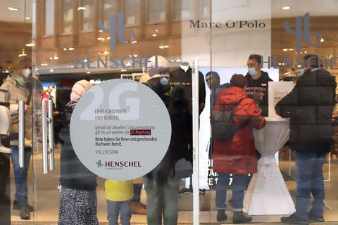 Am Eingang des Darmstädter Modehauses Henschel prüft eine Mitarbeiterin die Impfunterlagen eines Kundenpaares.  Foto: Andreas Kelm