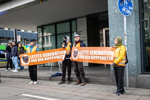 Nach ihrer Blockade der Rheinstraße demonstrieren die vier Aktivisten der "Letzten Generation" am Dienstagvormittag auf dem Gehsteig weiter. 