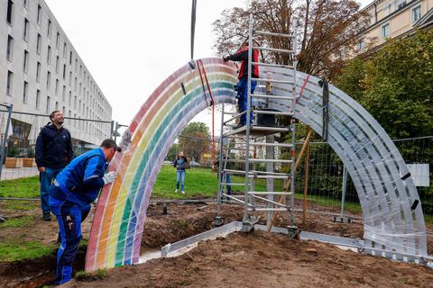 Passt! Künstler Matthias Braun (links) verfolgt, wie seine stählerne Regenbogen-Plastik am Ausgang des Herrngartens nahe dem Haus der Geschichte aufgebaut wird. Foto: Guido Schiek