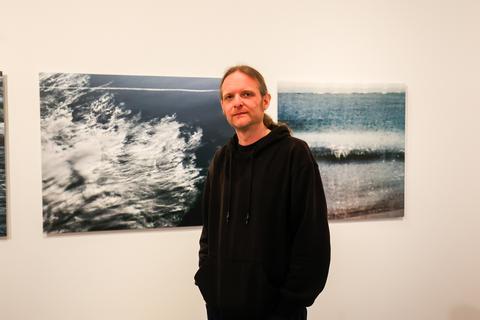 Fotograf Jan Kricke vor Wolken- und Wasserbildern.