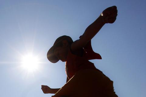 Ein Junge springt vor der strahlenden Sonne in die Weitsprunggrube.