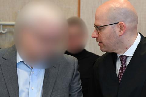 Der angeklagte ehemalige Frankfurter Oberstaatsanwalt (M) steht zum Prozessauftakt im Gerichtssaal des Landgerichts hinter dem mitangeklagten Geschäftsmann (l), der sich mit seinem Verteidiger Johannes Corsten unterhält.