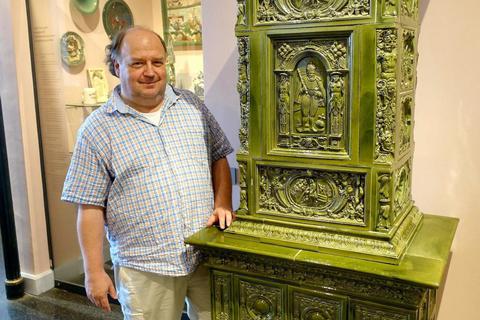 Museumsmitarbeiter Lothar Lammer zeigt im Dieburger Fechenbach-Schloss einen Kachelofen mit Kacheln der Firma Tonwaren Grießinger. Foto: Michael Prasch