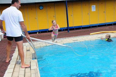 Die sechsjährige Emily Frank (Mitte) beim Schwimmkurs von Engin Ürün im Freibad in Groß-Umstadt. Die Rettungsstange des Trainers kann zur Not Halt geben. Foto: Winkler