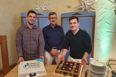 Abschied in den Ruhestand: Carlo Schneider (Mitte) freute sich über zwei Kuchen in symbolischer Kofferform von Daniel (links) und Jonny Heymanns (rechts), die den Pflegedienst „Heymanns & Schneider” in Münster weiterführen.