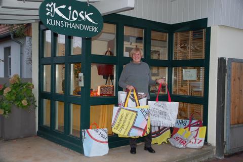 Elke Reuter vom Kiosk Kunsthandwerk in Seeheim zeigt einen Teil der Bannertaschen-Kollektion, die am Samstag, 12. November, auf dem Wochenmarkt erhältlich sein wird. Foto: Gemeinde Seeheim-Jugenheim