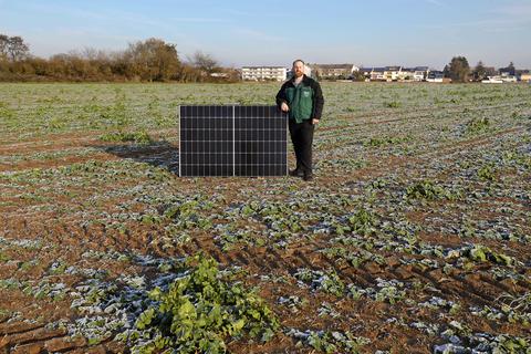Landwirt Patrick Meinhardt (CDU) mit einem Solarmodul auf dem Gelände für den geplanten Solarpark.