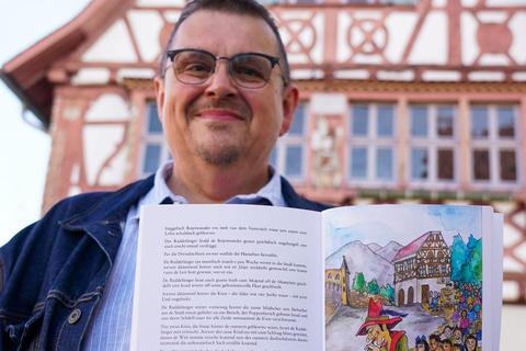 Uwe Plahuta präsentiert seinen Teil der Mundart-CD mit „Der Rattenfänger von Hameln“ vor dem historischen Büttelborner Rathaus. Foto: Marc Schüler