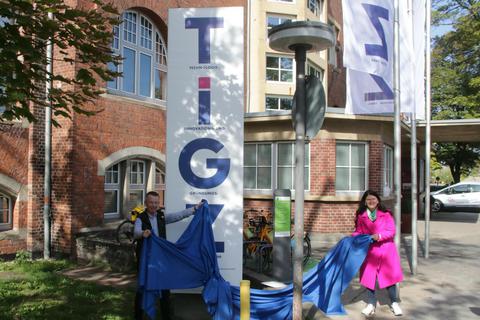 Vor dem TIGZ-Gebäude steht ein neuer Pylon, daneben wehen die Flaggen. Landrat Thomas Will und TIGZ-Geschäftsführerin Petruta Tatulescu übergaben die Konstruktion ihrer Bestimmung. Foto: Ralph Keim