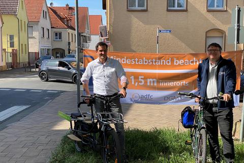 Bürgermeister Jan Fischer (links) und ADFC-Kreisvorsitzender Mario Schuller weisen mit Plakaten auf den Mindestabstand beim Überholen von Radfahrern hin. Nicht alle Autofahrer kennen diese Verkehrsregel.