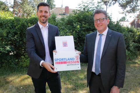 Bürgermeister Jochen Engel (links) erhielt von Staatssekretär Stefan Sauer den Förderbescheid über 50 000 Euro aus dem Sonderinvestitionsprogramm „Sportland Hessen“. Foto: Ralph Keim