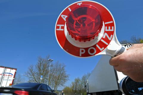 Ein Polizist hält eine Kelle mit der Aufschrift "Halt, Polizei". Symbolfoto: dpa
