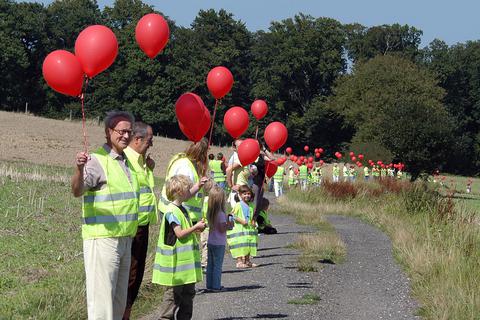 Mitglieder der Eschenhahner Bürgerinitiative für eine Ortsumgehung markieren mit roten Ballons die geplante Trasse der Umfahrung.