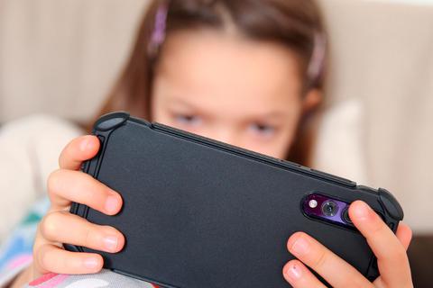 Ganz versunken: Viele Kinder spielen gerne am Handy - oft, weil sie dieses Verhalten von ihren Eltern übernommen haben..