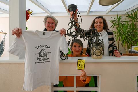 Noch drei Memorables sind geblieben: Ein T-Shirt, ein Aufkleber und eine Lampe, die (v.l.) Gerlinde Pursch, Noemi Olano Rodriguez und Edeltraud Scheliga, alle ehemals in der Tenne tätig, stolz zeigen. 