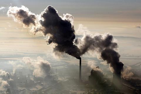 Luftaufnahme mit rauchenden Schornsteinen eines Kohlekraftwerks.