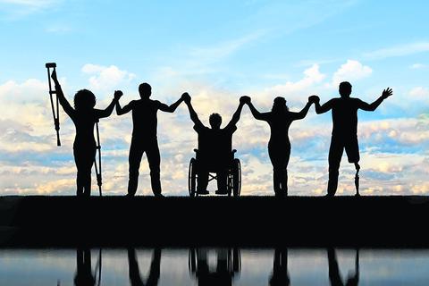 Behinderte Menschen auf Krücken und im Rollstuhl und Prothesen im Fuß und gesunde Menschen, die auf Regenbogenhintergrund stehen und Händchen halten. Konzept glücklich behindert
