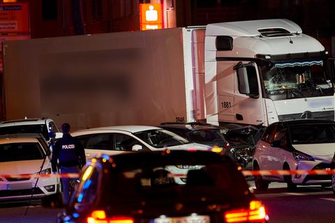Ein Polizist dokumentiert mit einer Kamera die von Scheinwerfern ausgeleuchtete Unfallstelle, an der ein  Lastwagen in Limburg auf mehrere vor einer roten Ampel vor dem Landgericht stehende Fahrzeuge aufgefahren ist. Foto: dpa