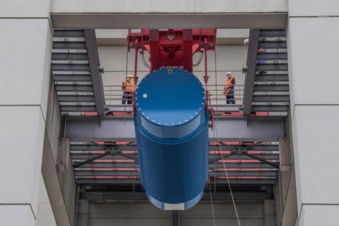 Mit Hilfe eines Schwerlastkranes heben Arbeiter einen blauen Castorbehälter in das Innere eines der Reaktorblöcke des Atomkraftwerk Biblis. Archivfoto: dpa