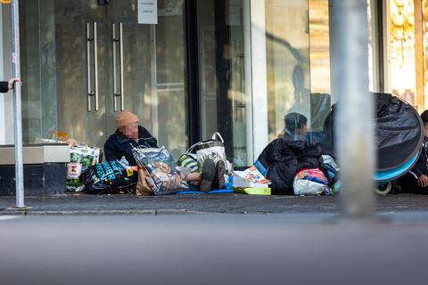 Obdachlose sitzen vor einem leer stehenden Geschäft in der Wiesbadener Fußgängerzone.