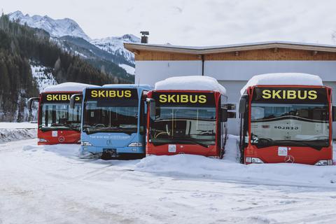 Schneebedeckte Skibusse stehen nebeneinander auf einem Parkplatz im österreichischen Tirol. Archivfoto: dpa