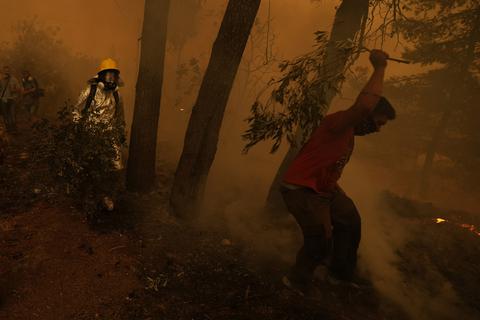 Personen versuchen einen Waldbrand in einem rauchverhangenen Waldstück in der Nähe des Dorfes Pefki auf der Insel Euböa zu löschen. Foto: Petros Karadjias/AP/dpa