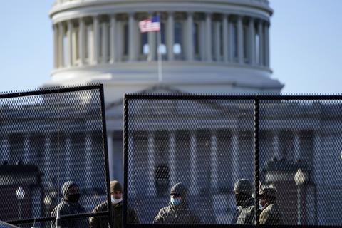 Beamte stehen hinter dem neuen Sicherheitszaun, der rund um das Kapitol errichtet wurde, nachdem am Tag zuvor Anhänger des scheidenden US-Präsidenten Trump gewaltsam das Parlamentsgebäude gestürmt hatten. Foto: dpa