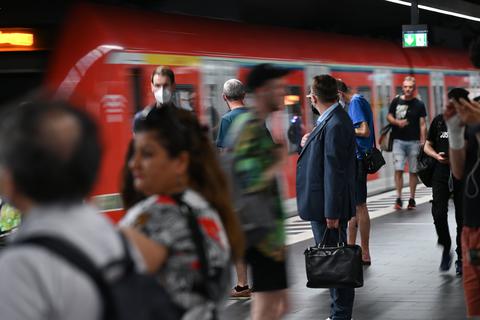 Zugreisende warten im Hauptbahnhof auf die Einfahrt einer S-Bahn.