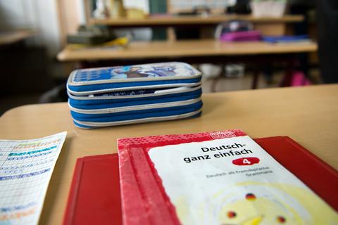 Auf einem Schultisch in einer Vorbereitungsklasse mit Schülerinnen und Schülern mit Migrationshintergrund der 102. Grundschule "Johanna" in Dresden liegen ein Heft «Deutsch ganz einfach» und weitere Schulmittel. Foto: dpa