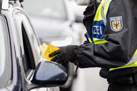Ein Bundespolizist kontrolliert den Impfpass einer einreisenden Person.  Foto: Matthias Balk/dpa 