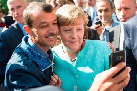 Bundeskanzlerin Angela Merkel (CDU) lässt sich am 10. September 2015 nach dem Besuch einer Erstaufnahmeeinrichtung für Asylbewerber der Arbeiterwohlfahrt (AWO) und der Außenstelle des Bundesamtes für Migration und Flüchtlinge in Berlin-Spandau für ein Selfie zusammen mit einem Flüchtling fotografieren. Foto: dpa 