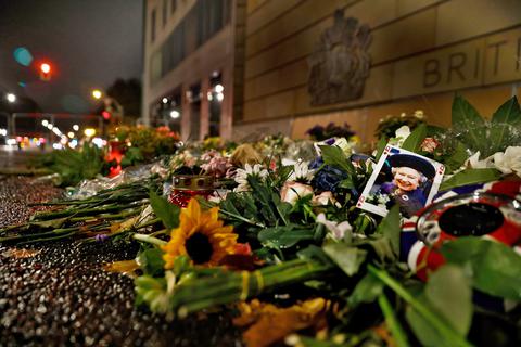 Blumen und ein Foto liegen als Zeichen der Trauer nach dem Tod der britischen Queen Elizabeth II. vor der Britischen Botschaft. Am heutigen Montag findet in London das Begräbnis im Beisein von zahlreichen internationalen Staatsoberhäupter statt.  Foto: Carsten Koall/dpa