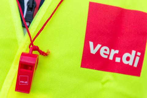 Ein Streikender trägt eine Warnweste mit dem Verdi-Logo und eine rote Trillerpfeife.  Foto: dpa