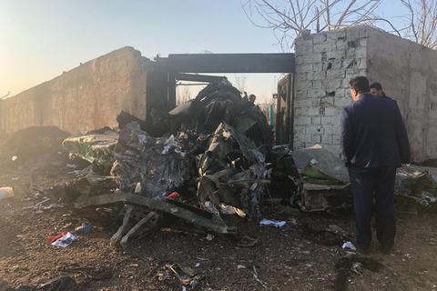 Männer begutachten nach dem Absturz einer Passagiermaschine am Rande von Teheran die Trümmerteile. Foto: dpa