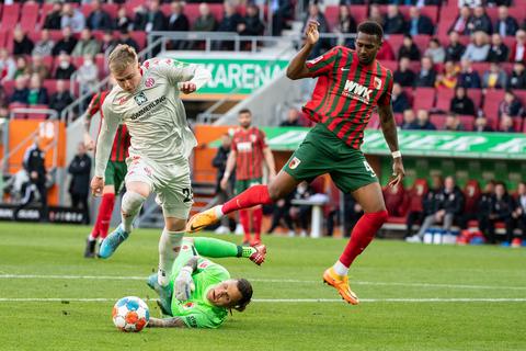 Am 26. Spieltag der Vorsaison kämpfen Jonathan Burkardt von Mainz 05 (l), Torwart Rafal Gikiewicz von Augsburg (M) und Reece Oxford von Augsburg um den Ball.  Foto: Matthias Balk/dpa