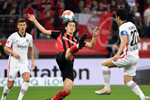 Leverkusens Sardar Azmoun (Mitte) und Frankfurts Makoto Hasebe (re.) kämpfen um den Ball. Dahinter sieht Frankfurts Ajdin Hrustic zu.  Foto: dpa/ Federico Gambarini