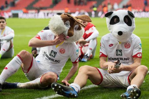 Im Fastnachtsmodus: Fabian Frei (l) und Gaetan Bussmann sitzen nach der Partie gegen Leverkusen mit Karnevalsmasken vor der Fankurve. Foto: dpa 