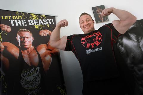 Markus Rühl („The Beast“) posiert vor einem Plakat, das ihn in seiner alten Bestform zeigt. Heute ist der 49-Jährige vor allem Geschäftsmann, YouTuber und Familienvater. Archivfoto: Karl-Heinz Bärtl