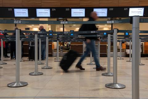 Ein Reisender geht mit einem Koffer zu einem Check-in-Schalter. Die Gewerkschaft Verdi hat für Mittwoch einen ganztägigen Warnstreik am Hauptstadtflughafen BER angekündigt.